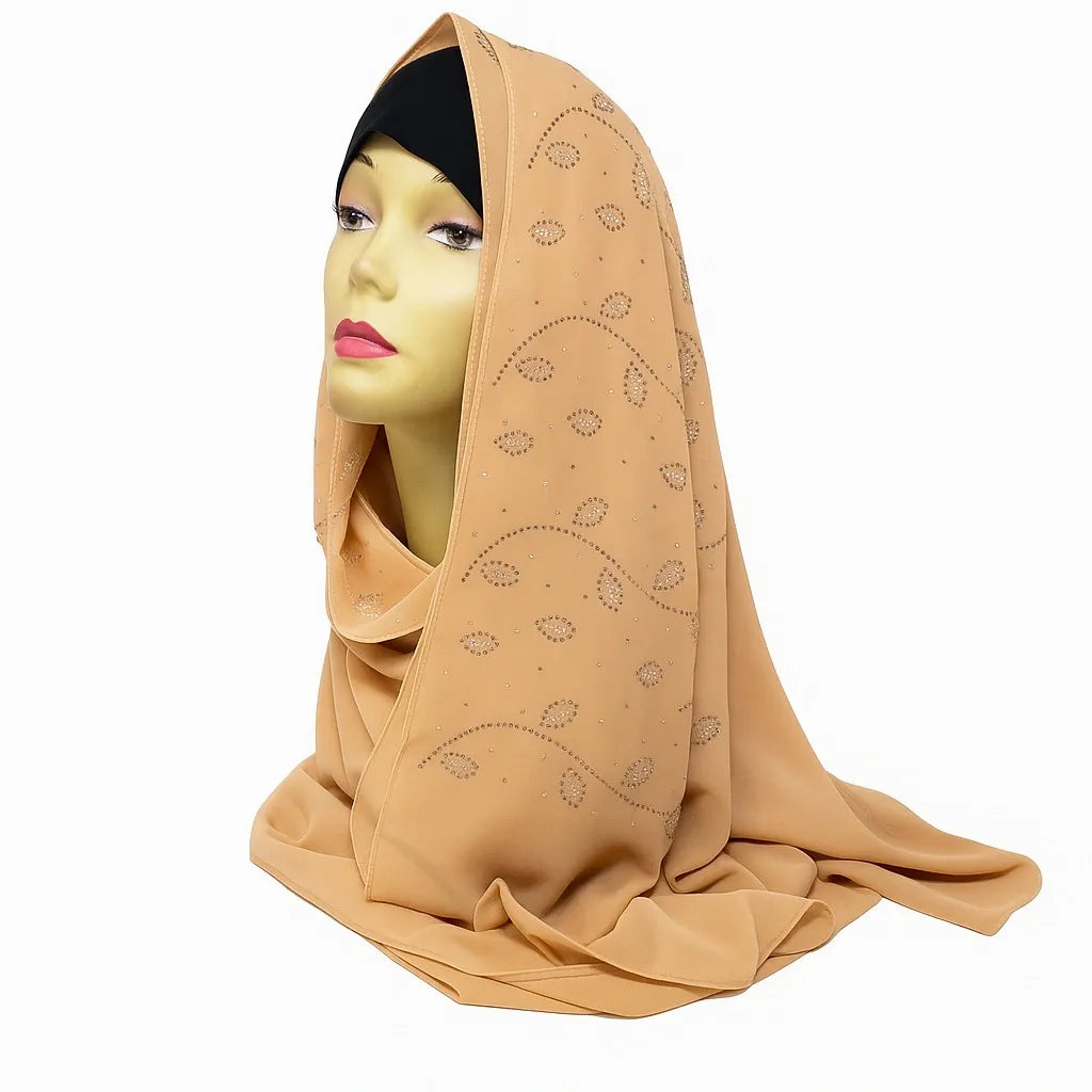 Beige chiffon hijab with rhinestone embellishments draped on mannequin, elegant modest fashion scarf for Muslim women, lightweight breathable chiffon headscarf suitable for Eid, weddings, and everyday wear.
