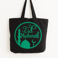 Black cotton tote bag with green Eid Mubarak circular design featuring crescent moon and mosque silhouette, reusable Islamic shoulder bag for Ramadan and Eid