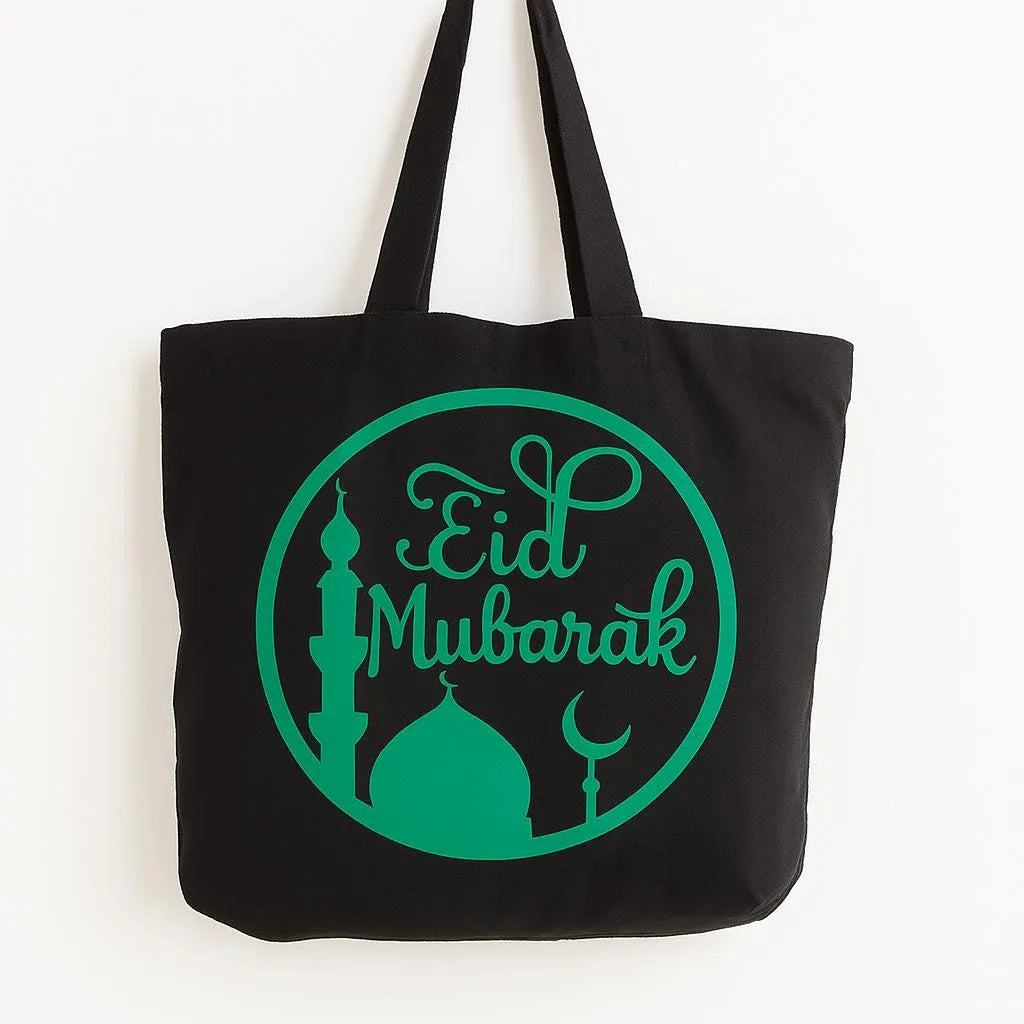 Black cotton tote bag with green Eid Mubarak circular design featuring crescent moon and mosque silhouette, reusable Islamic shoulder bag for Ramadan and Eid