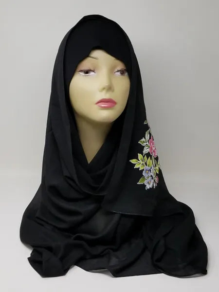 Black hijab scarf with colorful floral print on the side displayed on mannequin, modest Muslim headscarf for women, elegant black hijab wrap for everyday modest fashion and Islamic clothing.