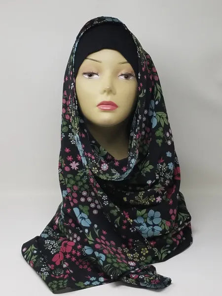 Black floral print hijab scarf with pink and green flowers for Muslim women displayed on mannequin, lightweight modest headscarf for everyday wear prayer and modest fashion styling