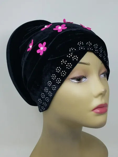Black velvet hijab bun cap with pink flower decoration and attached bun piece worn on mannequin head, modest under hijab cap designed to create bun shape for hijab styling from Affordable Hijab USA