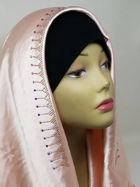 Blush pink satin hijab scarf with lace trim and rhinestone detailing along the edge, elegant modest fashion headscarf with smooth satin fabric drape designed for everyday wear, weddings, formal events, and stylish hijab outfits.