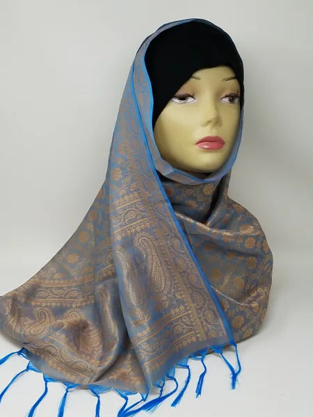 Brown and blue patterned hijab scarf with fringe edges draped on mannequin, lightweight modest wrap, soft textured fabric, full coverage stylish headscarf for everyday wear