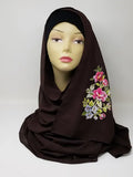 Dark brown hijab scarf with colorful floral print on the side displayed on mannequin, modest Muslim headscarf for women, elegant floral hijab wrap for everyday modest fashion and Islamic clothing.
