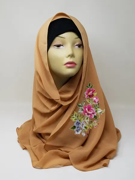 Camel brown hijab scarf with colorful floral print on the side displayed on mannequin, modest Muslim headscarf for women, elegant camel hijab wrap for everyday modest fashion and Islamic clothing.