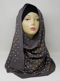 Charcoal gray chiffon hijab scarf with gold polka dot pattern displayed on mannequin head, lightweight modest fashion headscarf with soft drape perfect for everyday wear and stylish hijab outfits.