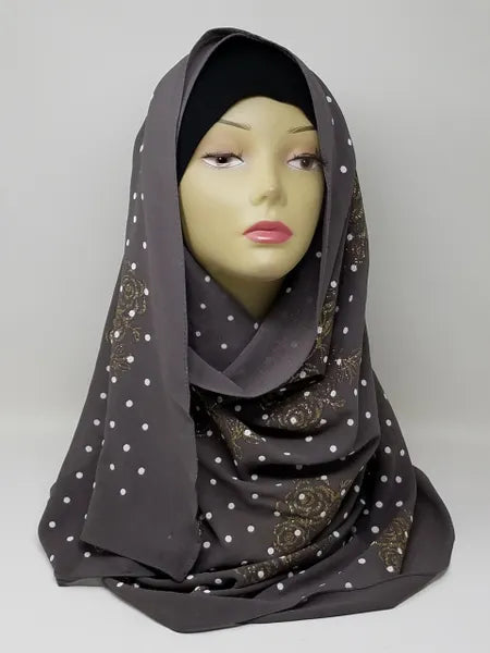 Charcoal gray chiffon hijab scarf with gold polka dot pattern displayed on mannequin head, lightweight modest fashion headscarf with soft drape perfect for everyday wear and stylish hijab outfits.