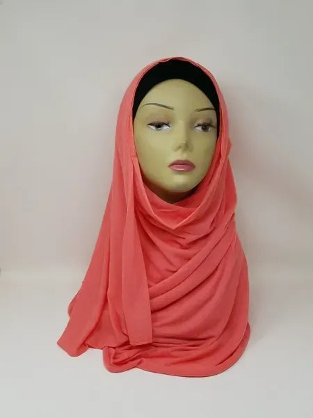 This coral jersey hijab is soft and easy to wear. It stretches gently and stays in place all day. The fabric feels light and smooth on your skin. It gives full coverage with a clean drape. No pins needed for most styles. Perfect for daily wear, work, or outings. The coral color is bright and fresh. Simple, comfortable, and easy to style every day.