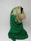 Elegant green hijab with gold beaded embroidery and rhinestone embellishments draped on mannequin head, luxury modest fashion scarf for weddings, Eid celebrations, and formal Islamic wear.
