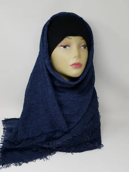 Navy blue hijab scarf draped on mannequin with textured finish and soft frayed edges, modest full coverage headscarf, lightweight breathable fabric, elegant wrap style shown from front and side view for everyday or casual wear