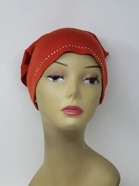 Bright orange undercap hijab worn on mannequin, snug stretch inner cap with small decorative edge detail, modest underscarf for secure fit under hijab, soft breathable fabric for everyday wear, front and side view