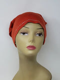 Bright orange undercap hijab worn on mannequin, snug stretch inner cap with small decorative edge detail, modest underscarf for secure fit under hijab, soft breathable fabric for everyday wear, front and side view