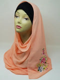 Peach hijab scarf with colorful floral print on the side displayed on mannequin, modest Muslim headscarf for women, elegant peach hijab wrap for everyday modest fashion and Islamic clothing.
