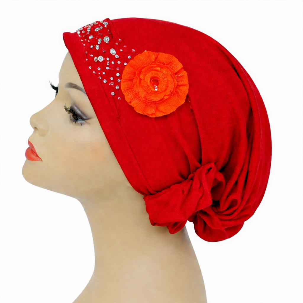 Red headscarf with an orange flower and embellishments on a mannequin head against a white background