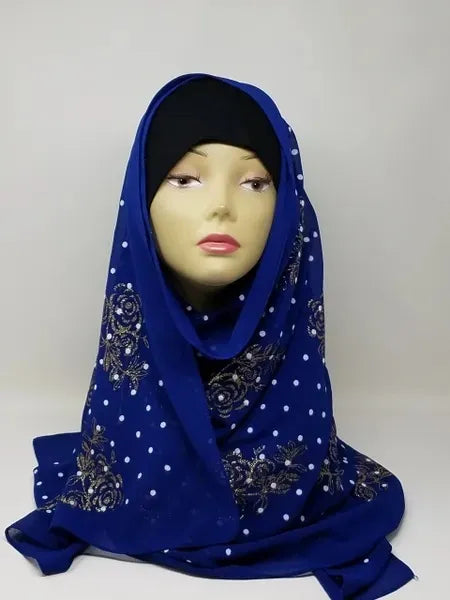 Royal blue chiffon hijab scarf with gold polka dot pattern displayed on mannequin head, lightweight modest fashion headscarf with soft drape perfect for everyday wear and elegant hijab styling.