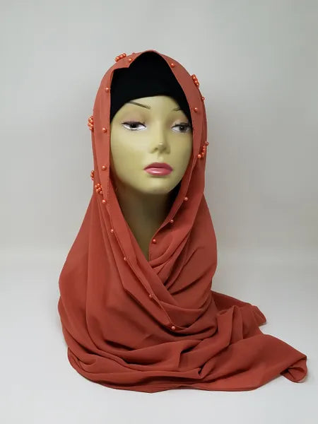 Rust color hijab scarf wrapped on mannequin, soft modest head covering, elegant draped style for everyday wear, simple plain design, lightweight look, full coverage hijab for women, neutral warm tone scarf, modest fashion accessory for daily outfit styling