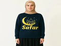 Woman wearing black Safar Islamic long sleeve shirt with gold crescent moon design, modest Muslim apparel on white background